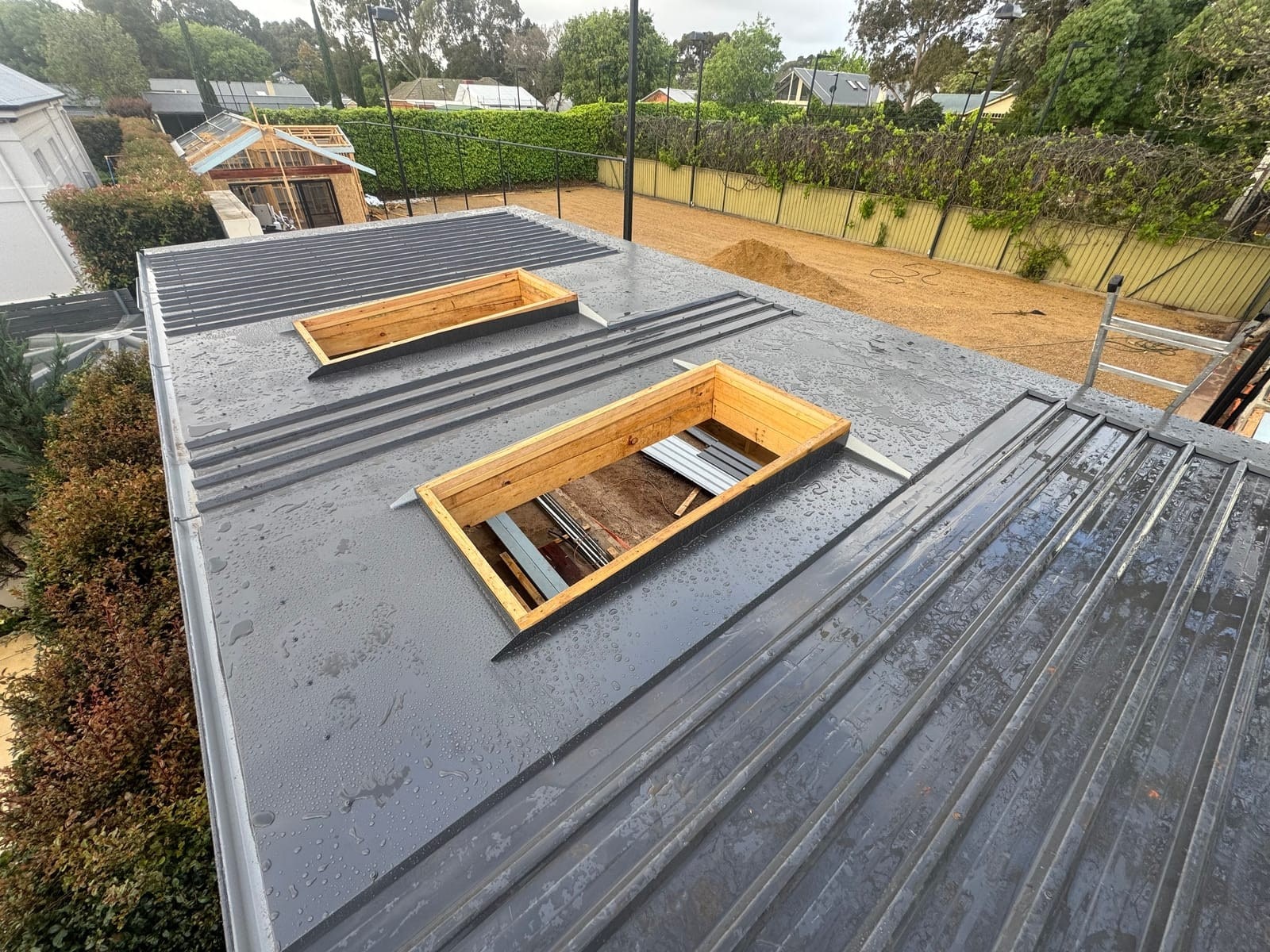 A flat metal roof with new skylight frames being fitted.