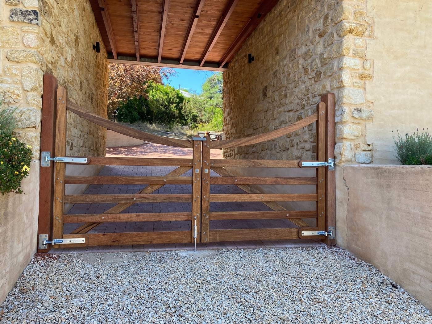 A pair of curved-top timber gates by Aston Rural Enterprises, hung in a sandstone entry.