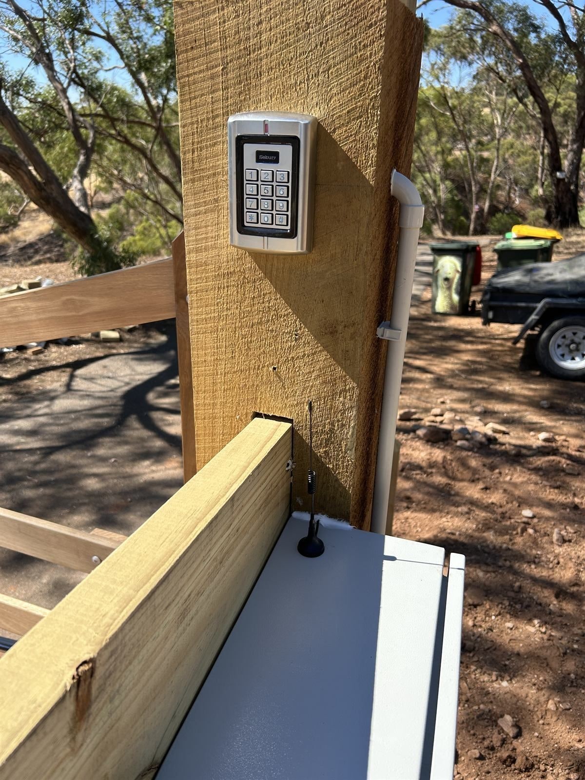 A keypad on its own post at a gate.