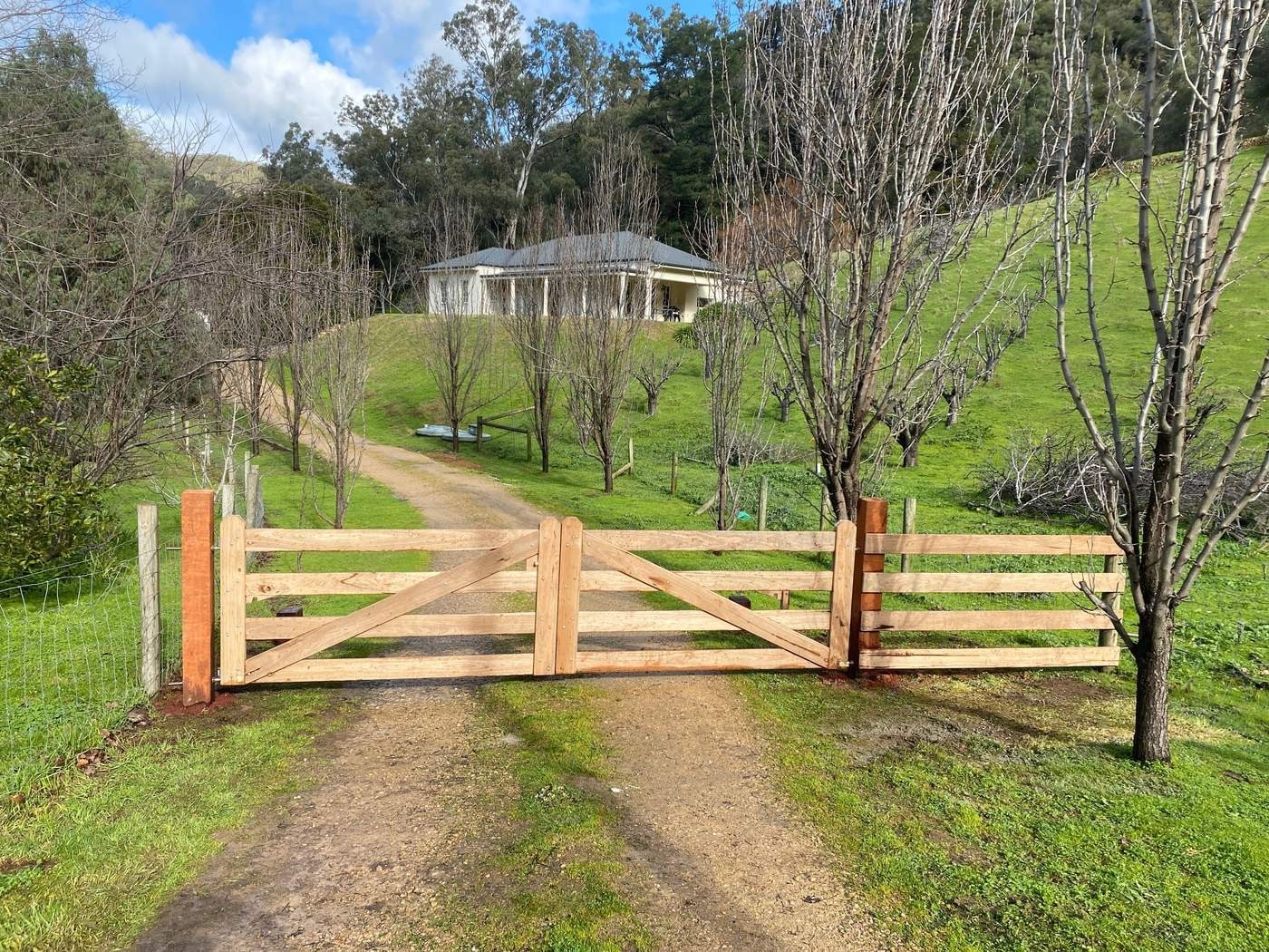 A rural driveway gate by Aston Rural Enterprises with hills behind.