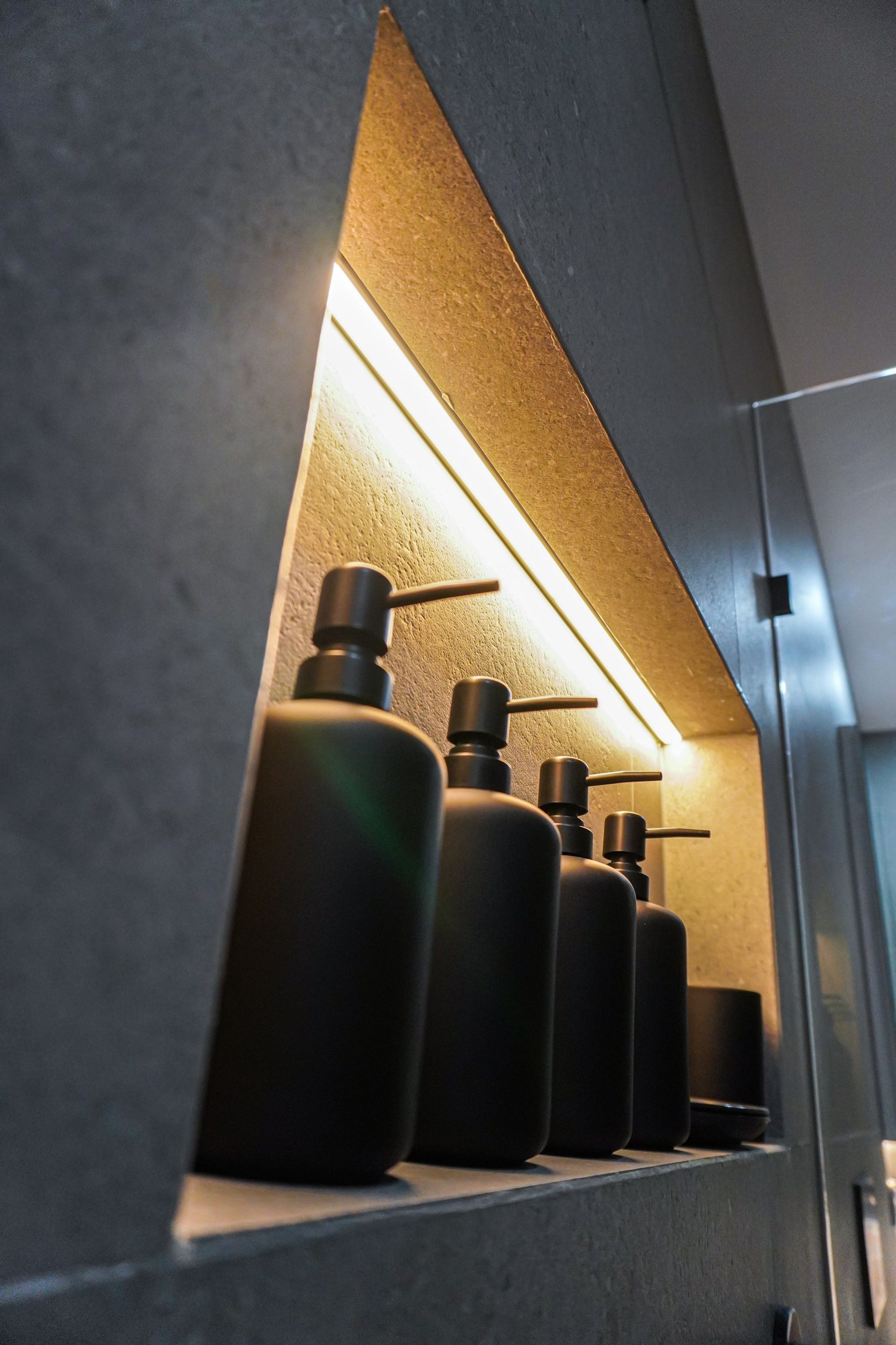 An LED-lit shower niche with black bottles in a Kingswood bathroom.