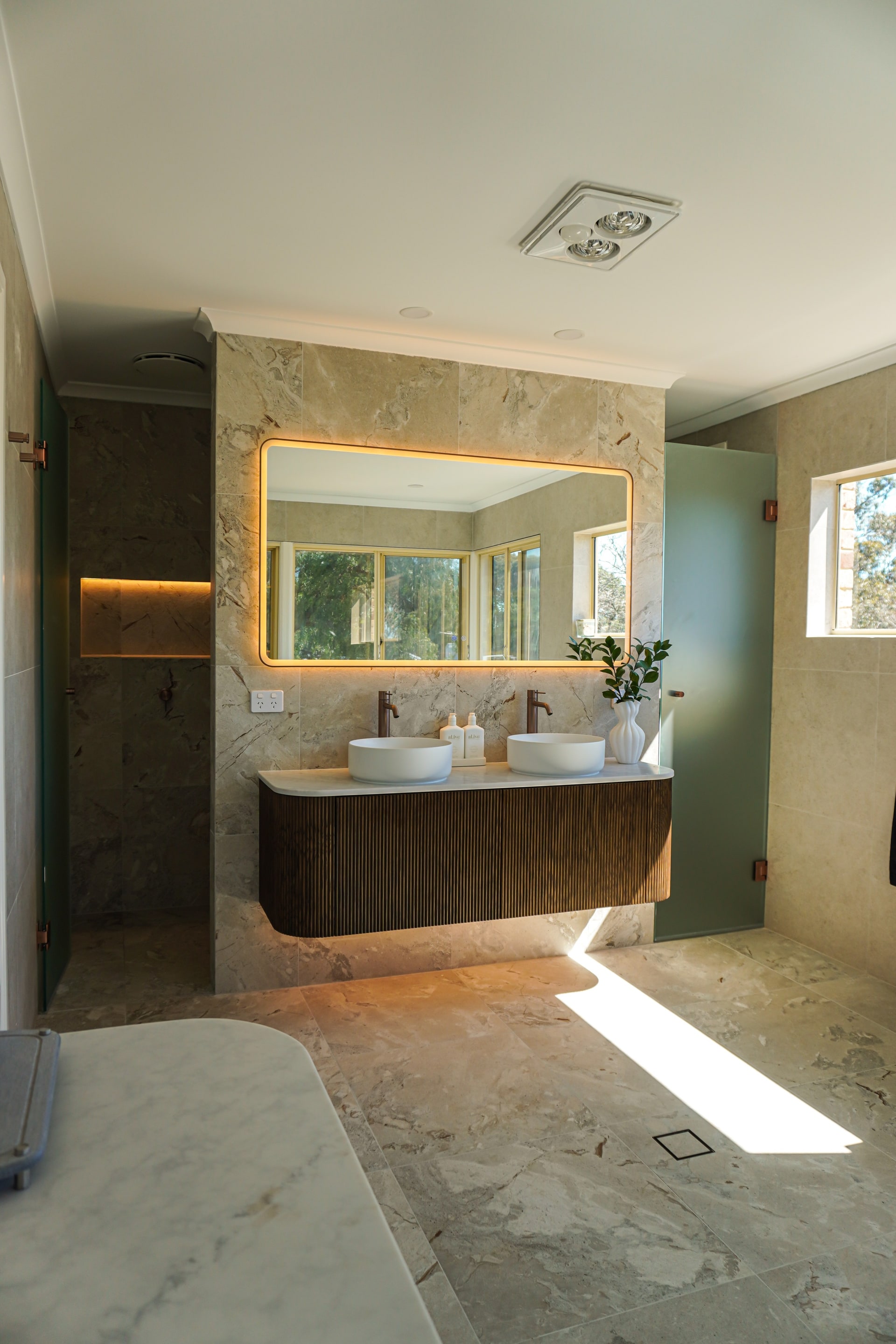 The Torrens Park master ensuite with a fluted timber vanity and backlit mirror.