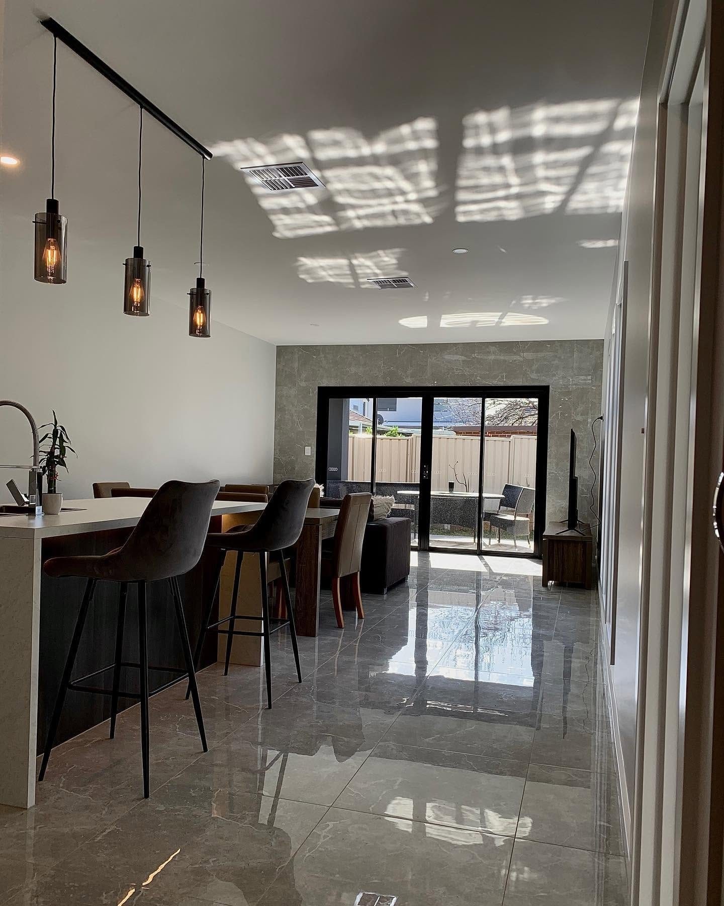 Large-format floor tiles through a living area, laid by Becks.