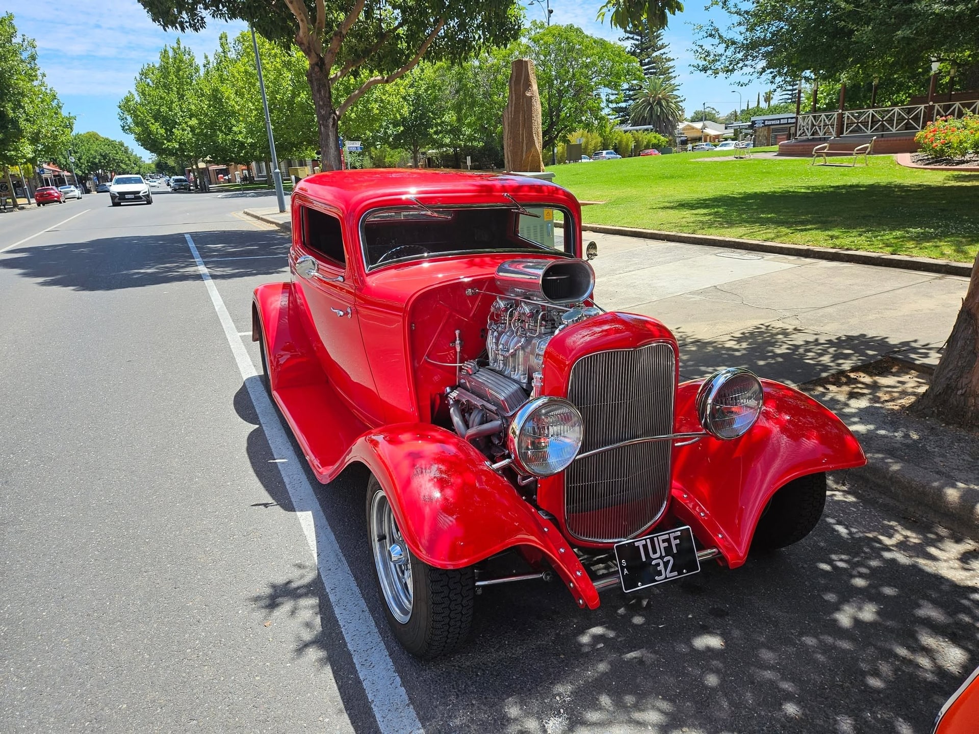 A red classic hot rod parked in the street outside the diner.