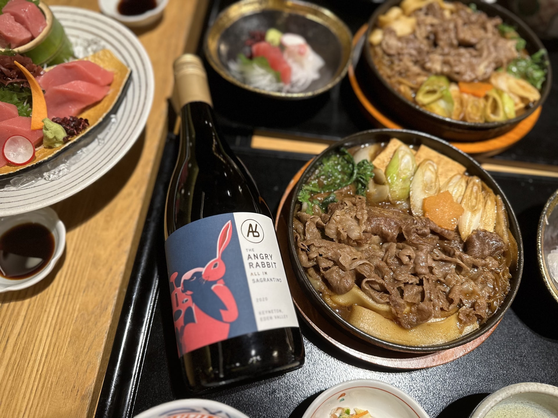 A bottle of The Angry Rabbit wine on a table of Japanese food.