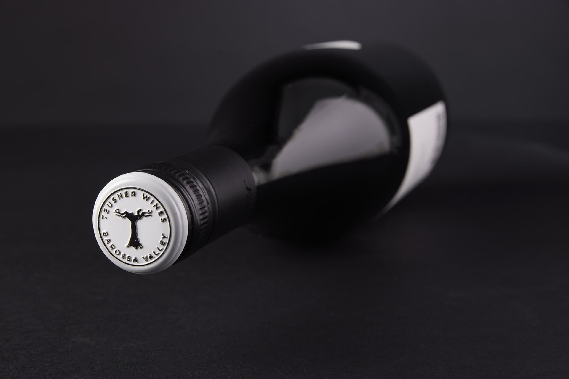A Teusner wine bottle cap on black.