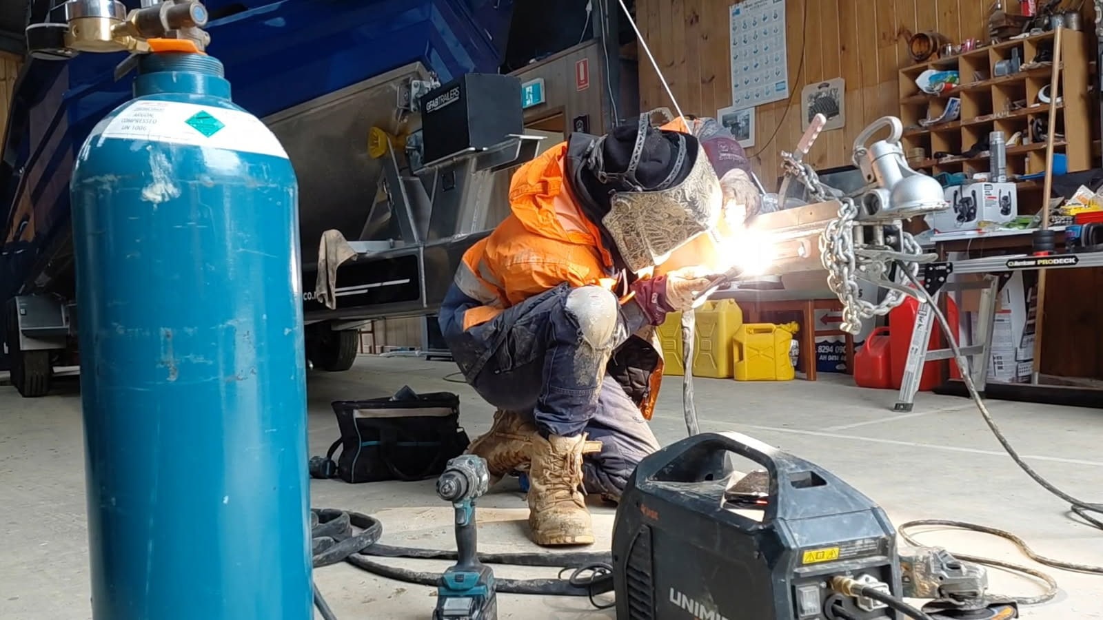 Sean from Iron Works Mobile Welding MIG welding in his workshop, sparks flying.