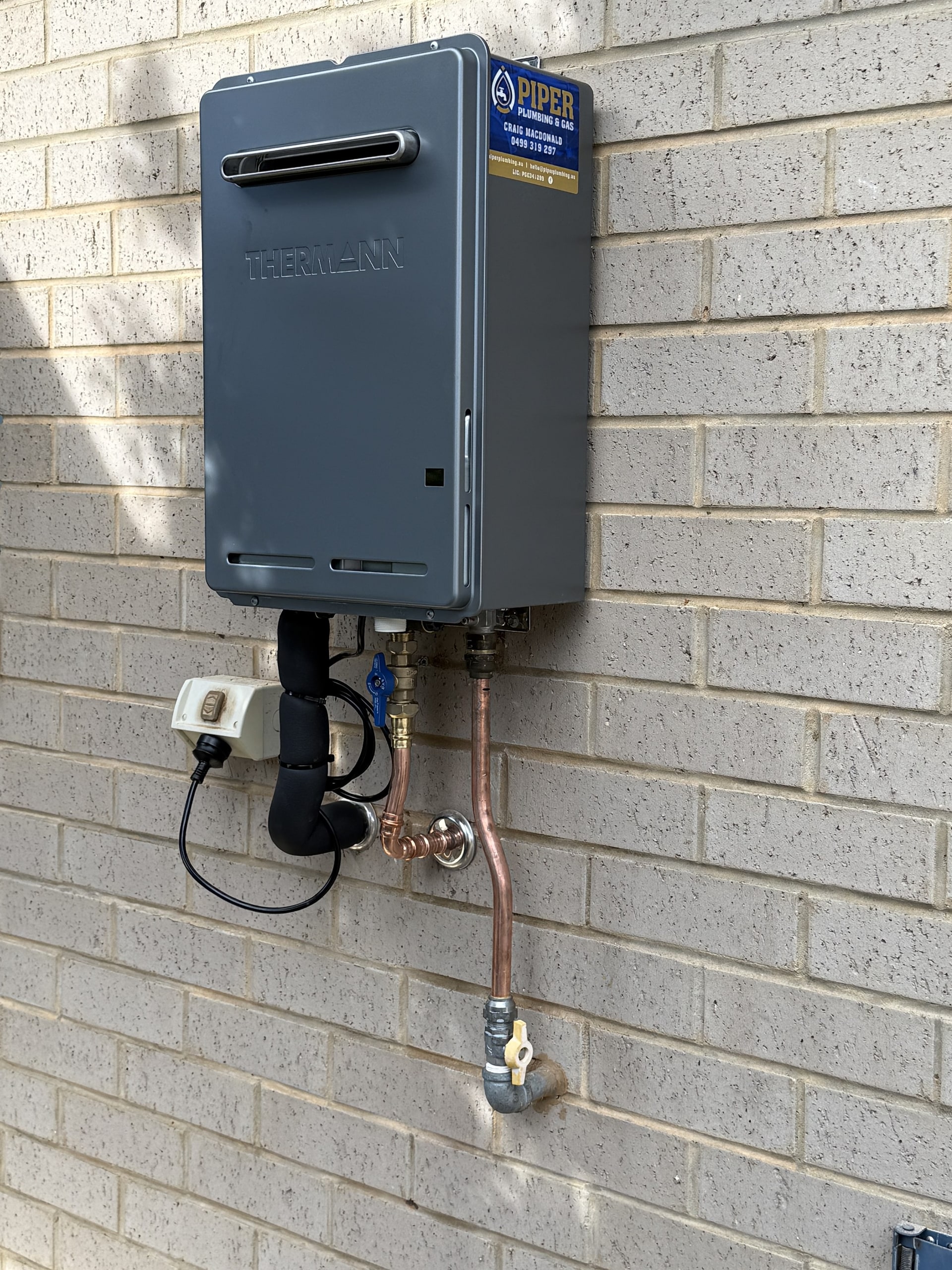 A newly installed gas hot water unit on an outside wall.