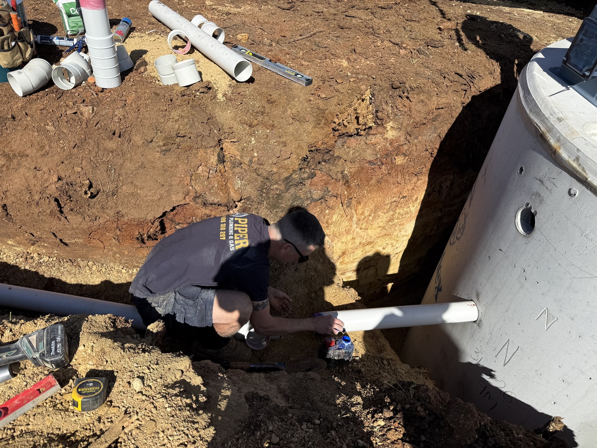 Pipework being fitted to a tank in an excavation on a rural job.