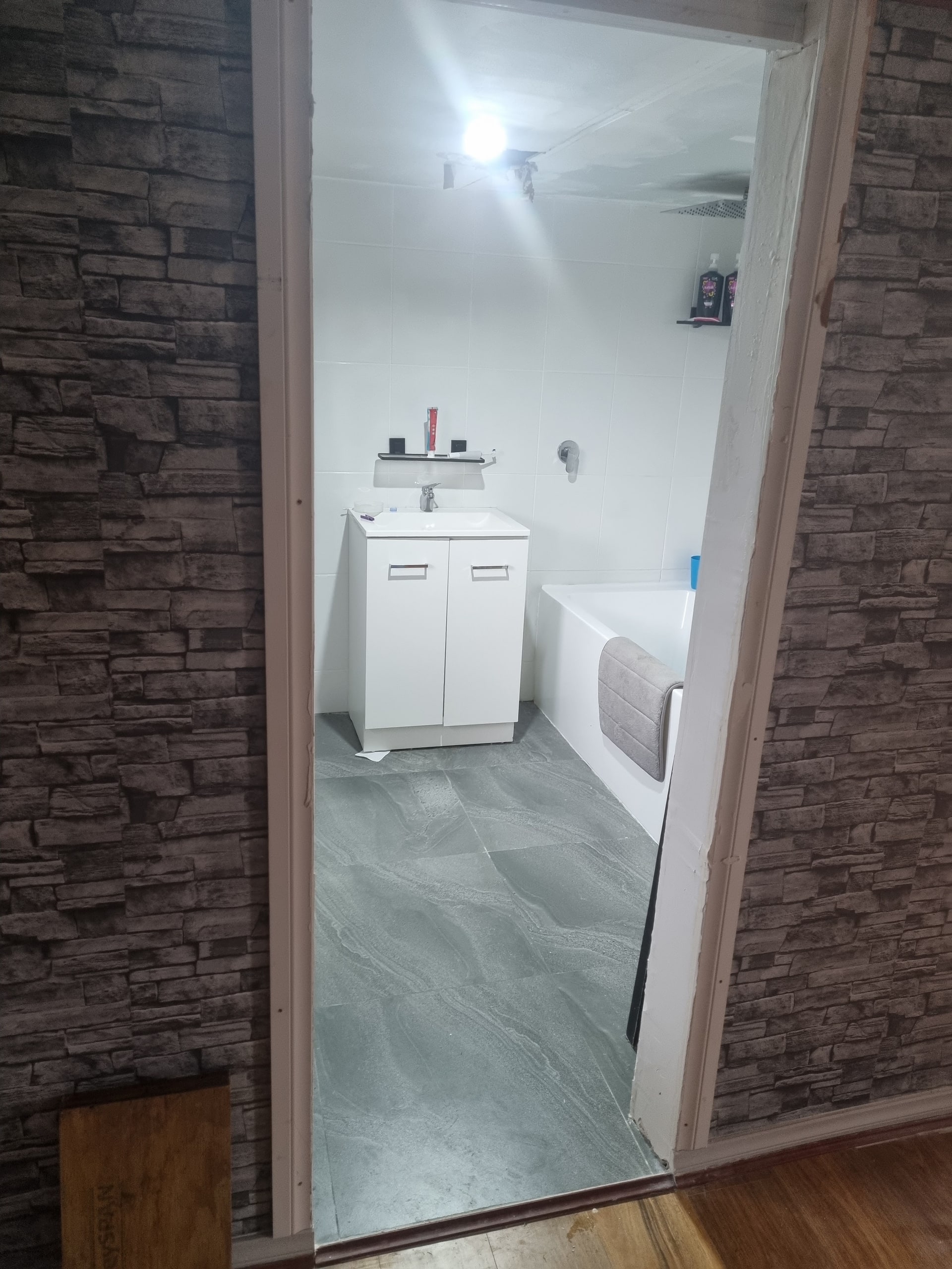 A bathroom doorway with a stone-look wall.