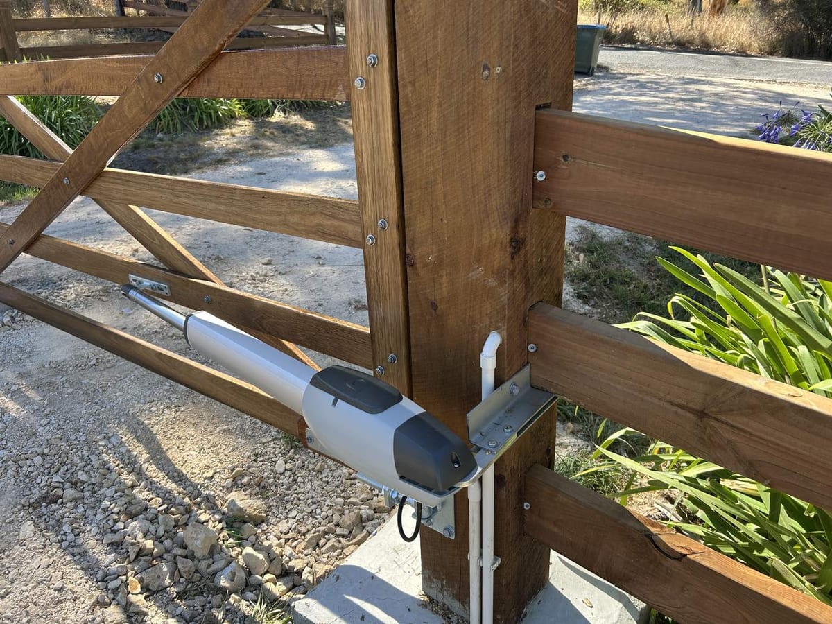 A gate motor arm fitted between a timber gate and its post.