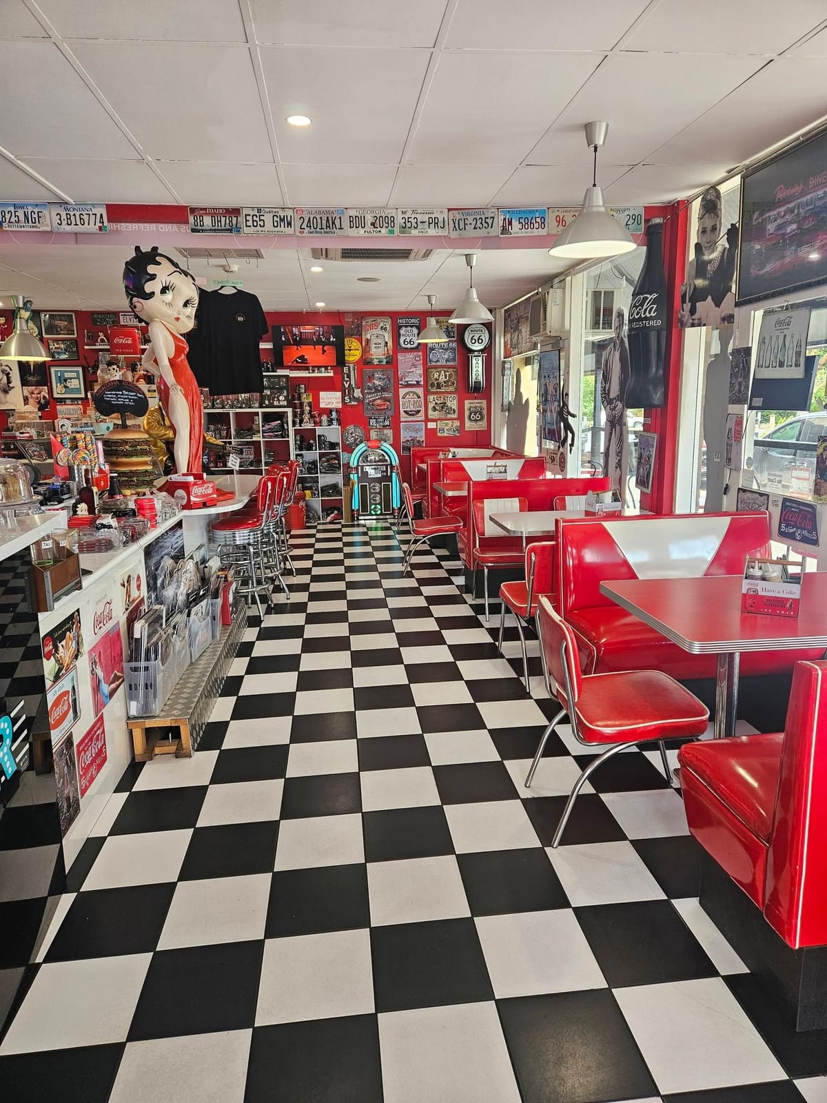 Inside Barossa 50’s Diner: red vinyl booths and chrome chairs along a black and white checkerboard floor, with memorabilia on every wall.
