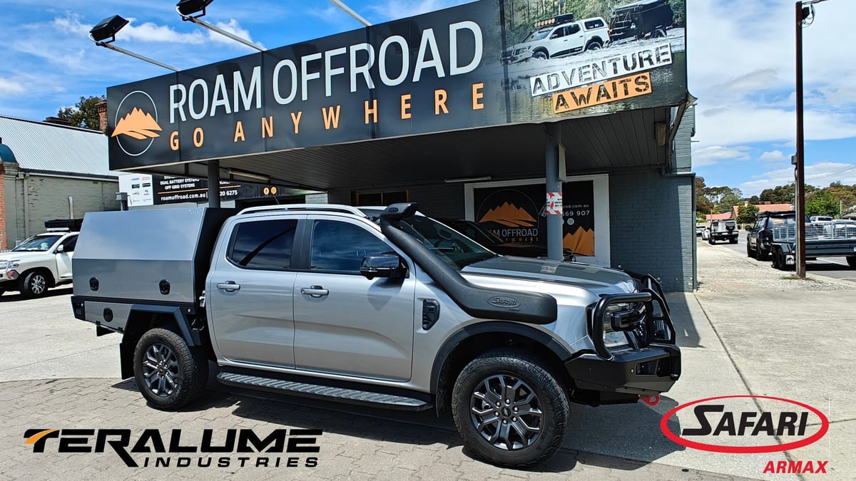 A silver Ford Ranger fitted with a Teralume aluminium canopy, parked outside the Roam Offroad shopfront.