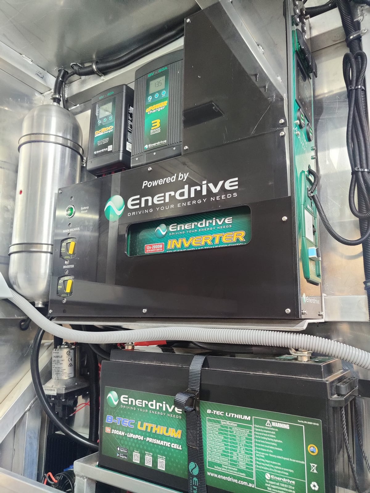 An Enerdrive inverter charger and lithium batteries mounted and wired in an aluminium compartment as part of an off-grid dual battery install.