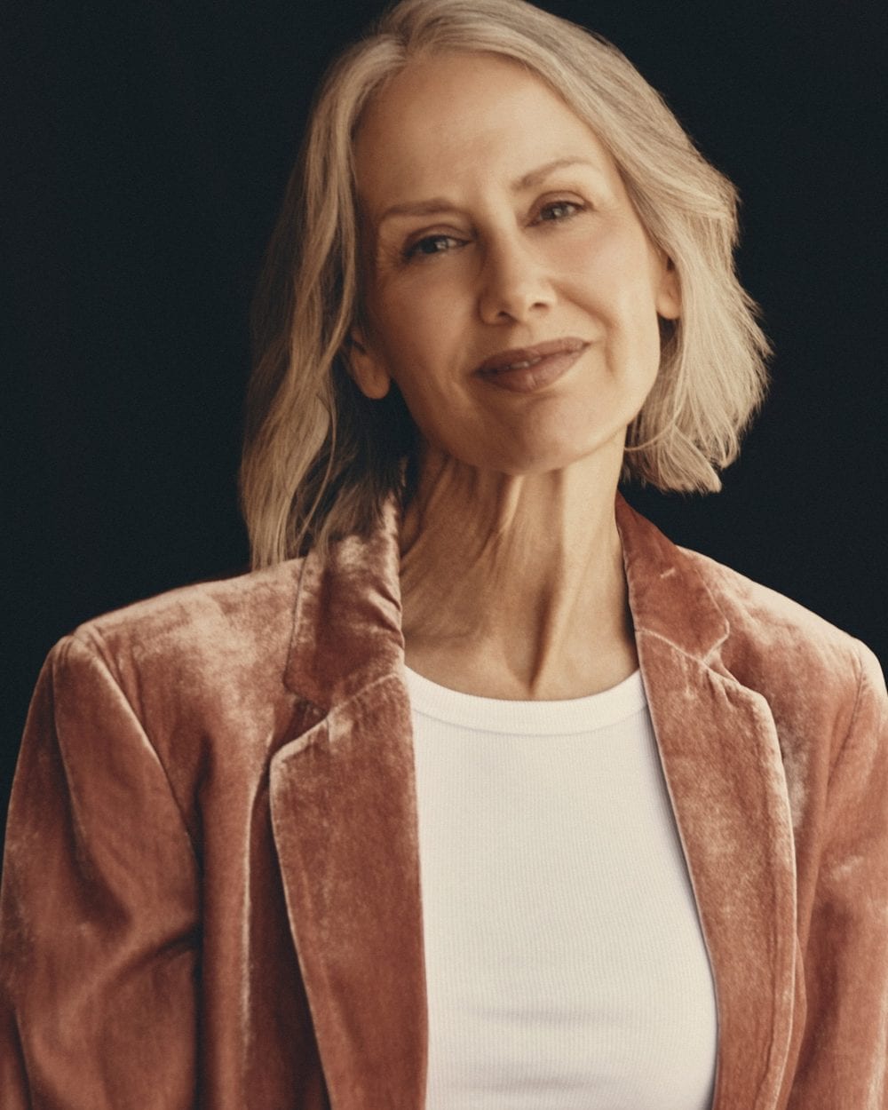 Portrait of Samantha Foreman in a dusty-rose crushed-velvet jacket and white top against a black background.