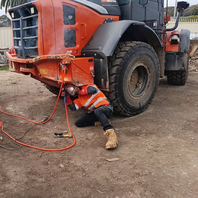 Iron Works Mobile Welding on site, welding a repair under a wheel loader: the business’s own job photo